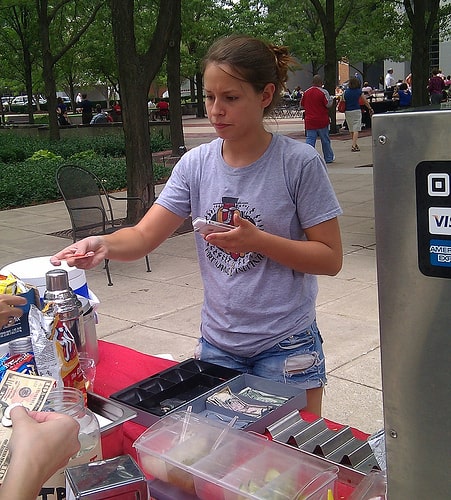 Mobile hot dog vendor accepts a credit card payment with a Square reader.