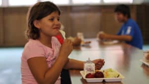 A girl smiles while eating a meal at Eagle Butte, South Dakota.