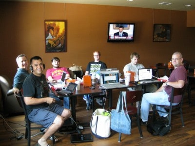 A diverse group of people with laptops sitting around a table, coworking. 