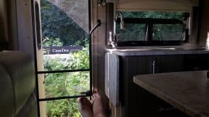 From inside an RV, the view shows a winery sign and grape vines