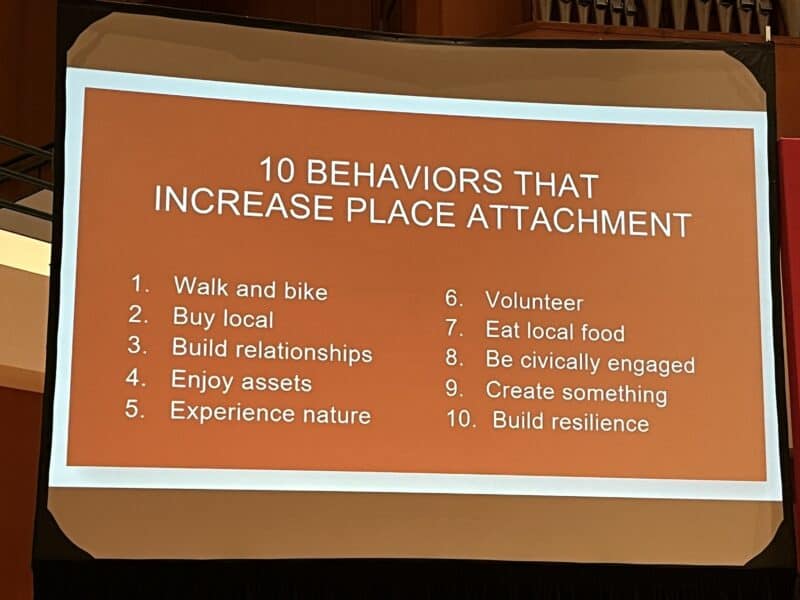 Slide with text. It says, "10 behaviors that increase place attachment. Walk and bike. Buy local. Build relationships. Enjoy assets. Experience nature. Volunteer. Eat local food. Be civically engaged. Create something. Build resilience." 