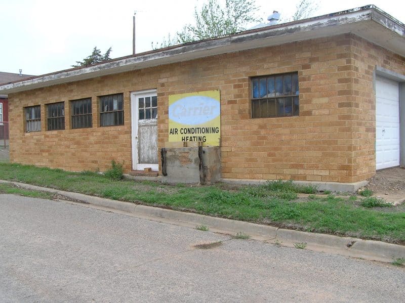 A building used as business storage with an old faded sign that says "Carrier Air Conditioning"