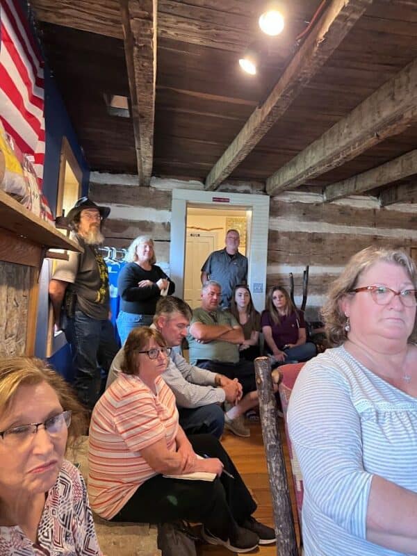 A group of people listening at a meeting in a rustic building. 