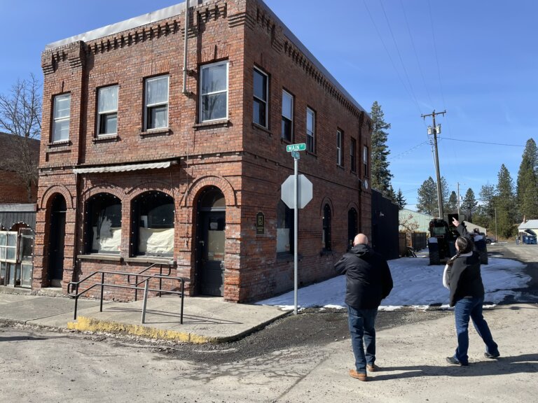 Two people are pointing to features on a brick building in a small town downtown